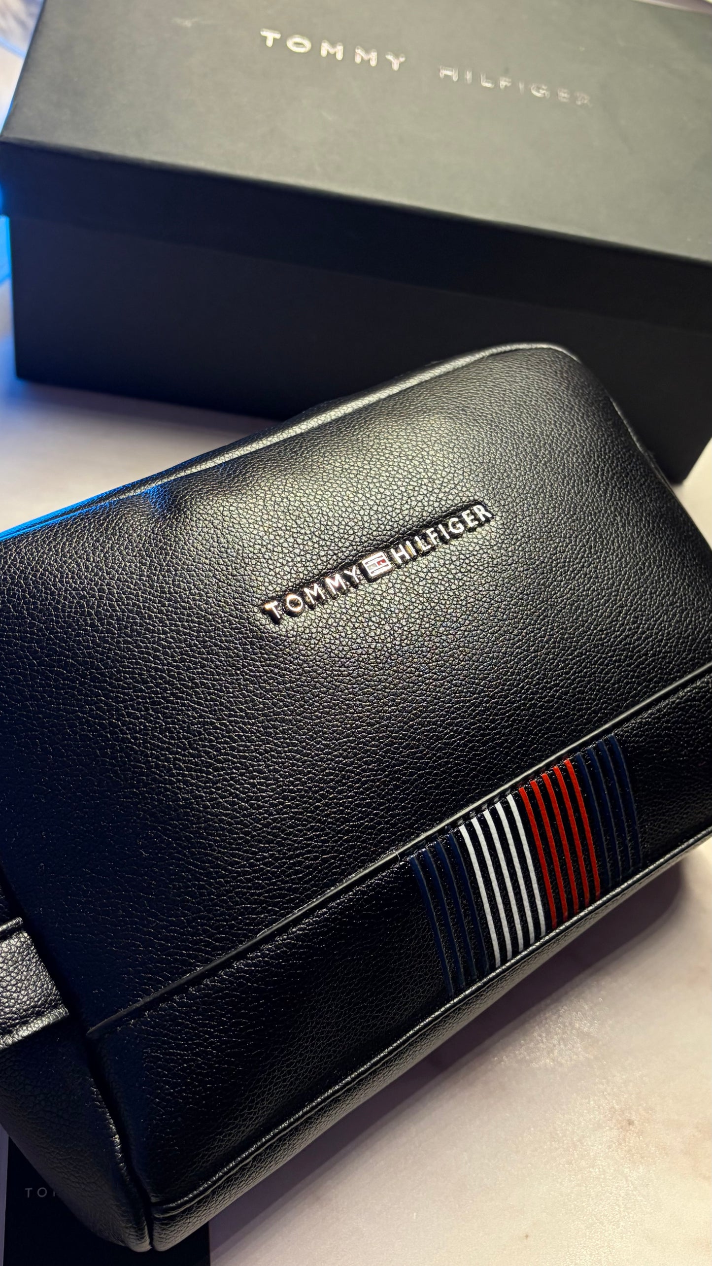 Black leather handbag with Tommy Hilfiger branding on a light surface.