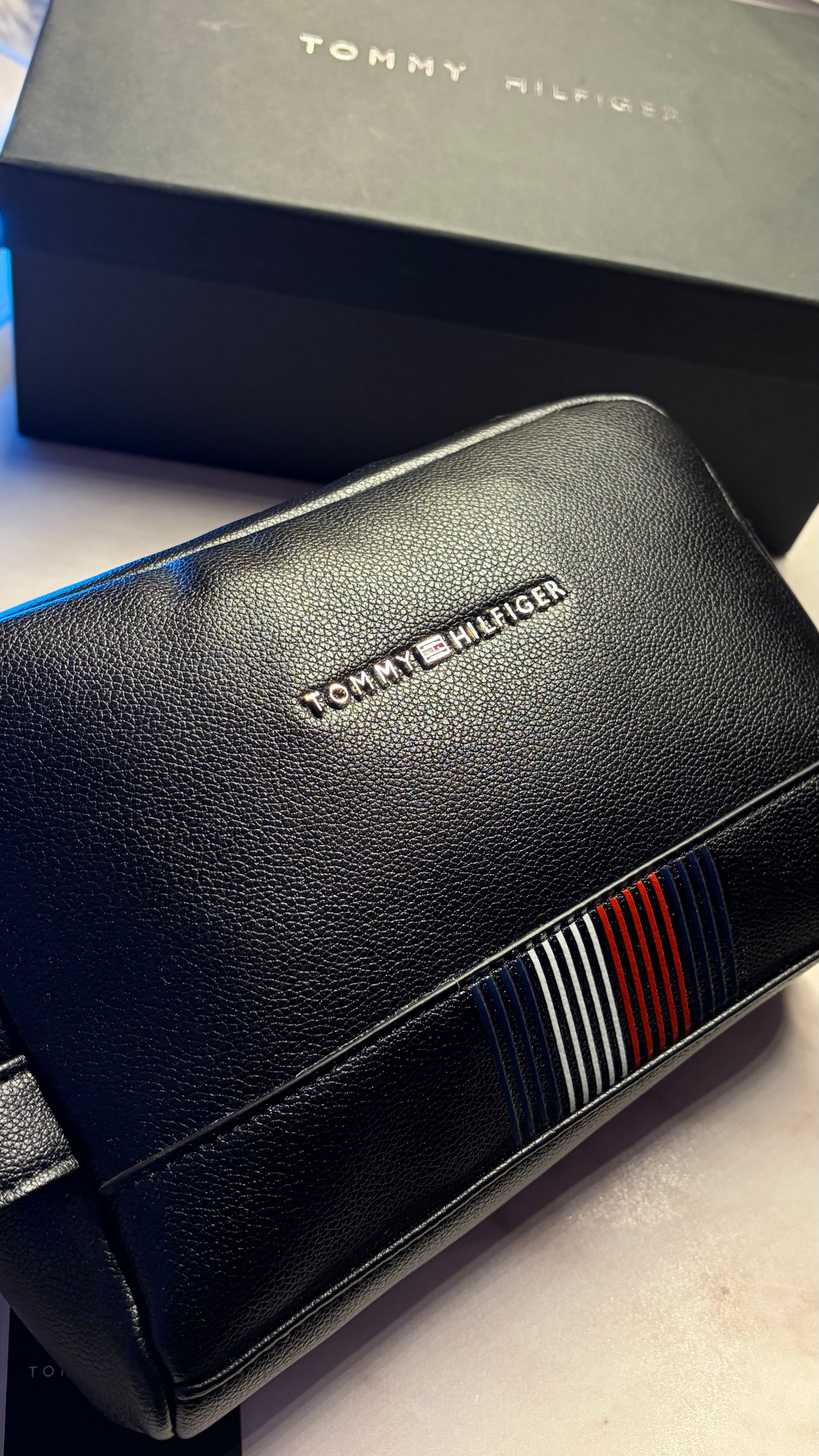 Black leather handbag with Tommy Hilfiger branding on a light surface.