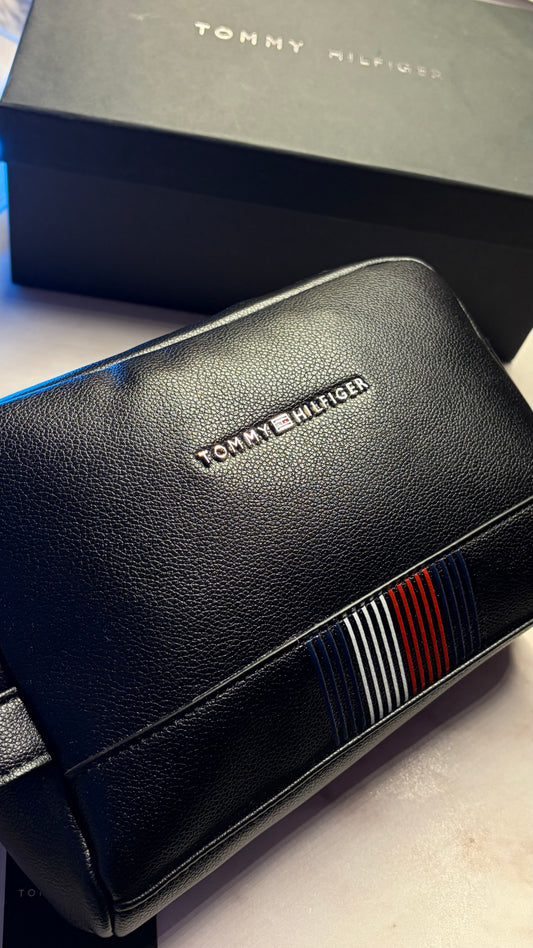 Black leather handbag with Tommy Hilfiger branding on a light surface.