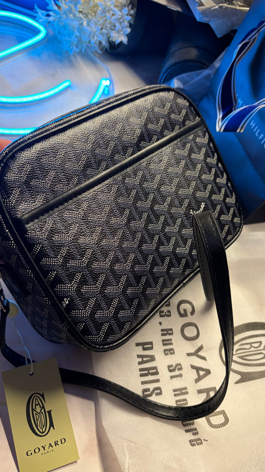 Goyard bag with a visible tag on a surface with a neon sign in the background